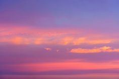 an airplane is flying in the sky at sunset or sunrise with pink and blue clouds