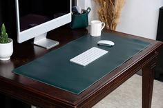 a computer desk with a keyboard, mouse and cup on it in front of a monitor