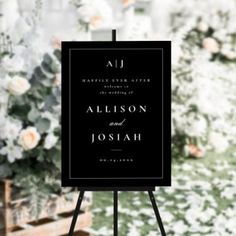 a black and white wedding sign sitting on top of a easel next to flowers