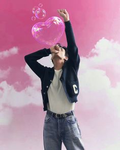 a man blowing bubbles into the air with his arms in the air while standing against a pink background