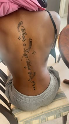 the back of a woman's body with tattoos on it