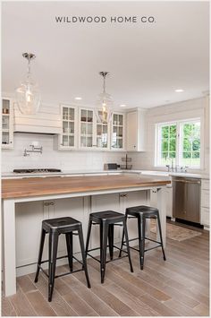 an image of a kitchen setting with bar stools and wood countertop in the center