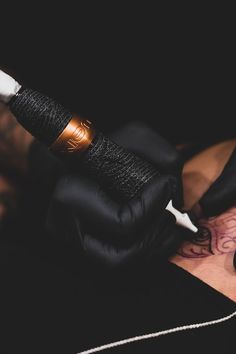 a man with tattoos on his arm holding a black and white object in his hand