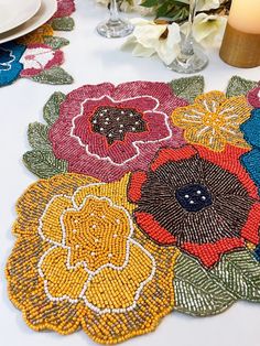 a table topped with lots of colorful flowers on top of a white table covered in candles