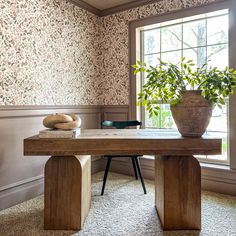 a wooden table sitting in front of a window next to a potted plant