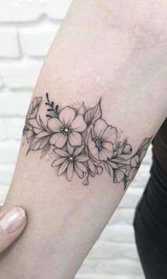 a black and white flower tattoo on the left arm, with flowers in it's center