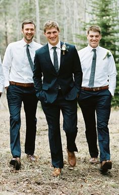 a group of men standing next to each other in front of some trees and grass