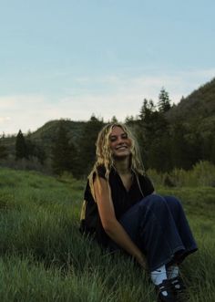 a woman is sitting in the grass smiling