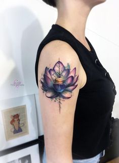 a woman with a tattoo on her arm has a purple flower in the shape of a cross