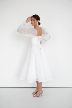 a woman in a white dress is posing for the camera with her hands on her head