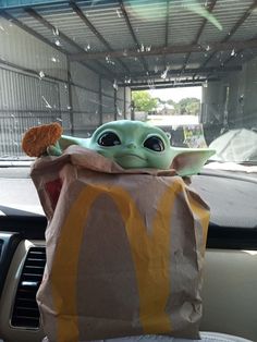 a baby yoda in a mcdonald's bag sitting on top of a car dashboard