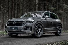 the front end of a grey volkswagen cayen parked on a road near some trees