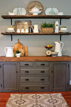 an old dresser is painted gray and has shelves with dishes on it, along with other items