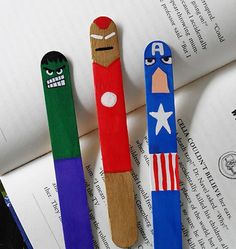 two wooden pencils decorated as captain america and iron man on top of an open book