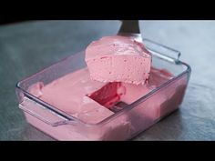 a pink cake in a plastic container with a knife