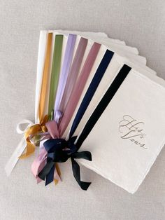 a bunch of different colored ribbons on top of a white cloth bag with the word hello written on it