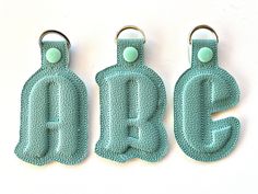 three key chains with the letters b, c, and e on them are made out of crochet