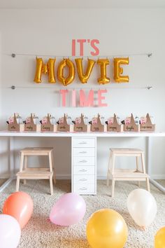 it's movie time party with balloons and wooden stools in front of the table