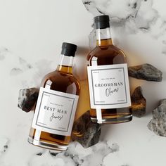 two bottles of groomsman's whiskey sitting next to each other on a marble surface