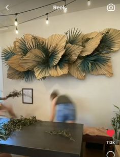 two people standing in front of a table with plants on it and hanging from the ceiling