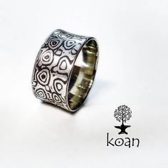 a silver ring with an intricate design on the inside, and a tree in the middle