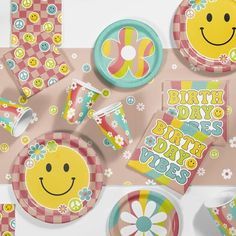 an assortment of birthday party supplies including plates, napkins and cups with smiley faces on them