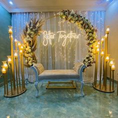 a couch sitting in front of a wall with candles and flowers on top of it