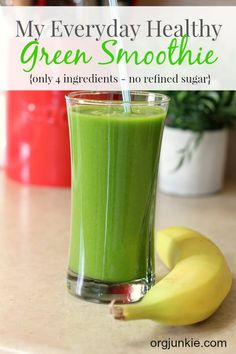 a green smoothie in a tall glass with a straw on the side and a banana next to it