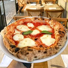 a pizza sitting on top of a white plate covered in sauce and mozzarella