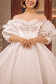 a woman in a white dress posing for the camera with her hands on her hips