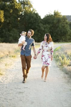 a man and woman walking down a dirt road holding hands