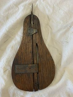 an old wooden instrument on a white sheet with a metal hook in the middle and a piece of wood sticking out of it