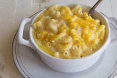 a white bowl filled with macaroni and cheese sitting on top of a plate