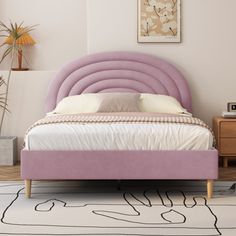 a bed with a pink headboard and foot board in a white room next to a rug