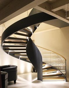 a spiral staircase in the middle of a room with white walls and carpeted flooring