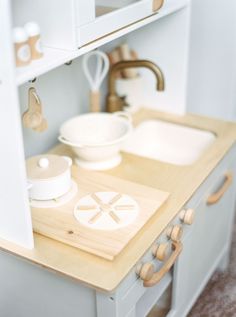 a toy kitchen with white dishes and wooden utensils