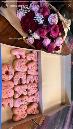 two boxes filled with doughnuts next to a bouquet of roses