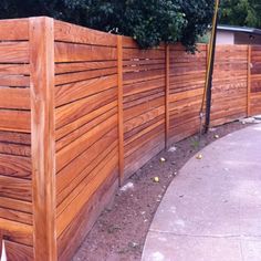 a wooden fence next to a sidewalk