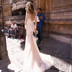 a woman in a wedding dress standing on the street