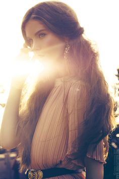 a woman with long hair standing in the sun