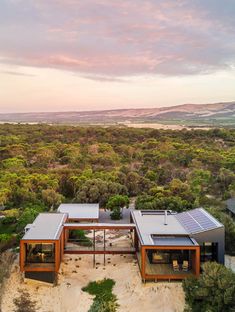 an aerial view of a house in the middle of trees and land with mountains in the background