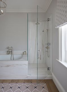 a bathroom with a walk in shower next to a bathtub and sink under a chandelier