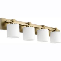 four light bathroom fixture with white shades on the lights and gold finish, in an aged brass finish