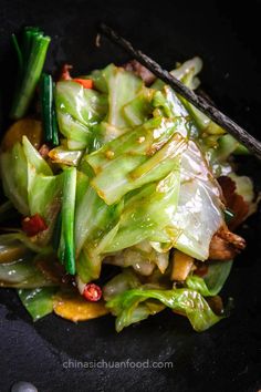 stir fried vegetables with chopsticks in a black bowl