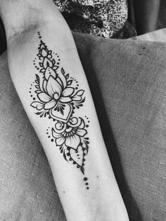 a black and white photo of a woman's arm with a flower tattoo on it