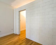 an empty room with white bricks on the wall and wood floors in front of it