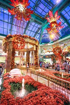 the inside of a building with flowers and chandeliers hanging from it's ceiling