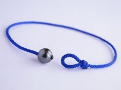 a blue string bracelet with a silver bead on it and a ball hanging from the end