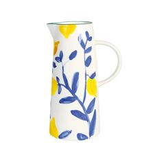 a white pitcher with blue and yellow flowers painted on the side, sitting in front of a white background