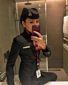 a woman taking a selfie in the bathroom while wearing an air force pilot's uniform